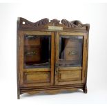 An oak smoker's cabinet, two half-glazed doors with four small drawers and pipe stands to interior,