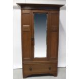 An Arts & Crafts oak wardrobe, mirrored door over single drawer with carved stylised leaf motifs,