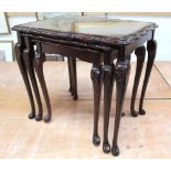 A reproduction mahogany nest of tables with scalloped and glazed tops on carved slender cabriole