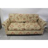 A modern two-seater settee upholstered in cream ground floral fabric,