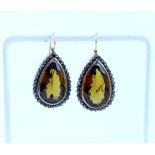 A pair of yellow metal earrings set with large brown topaz surrounded by chip diamonds.