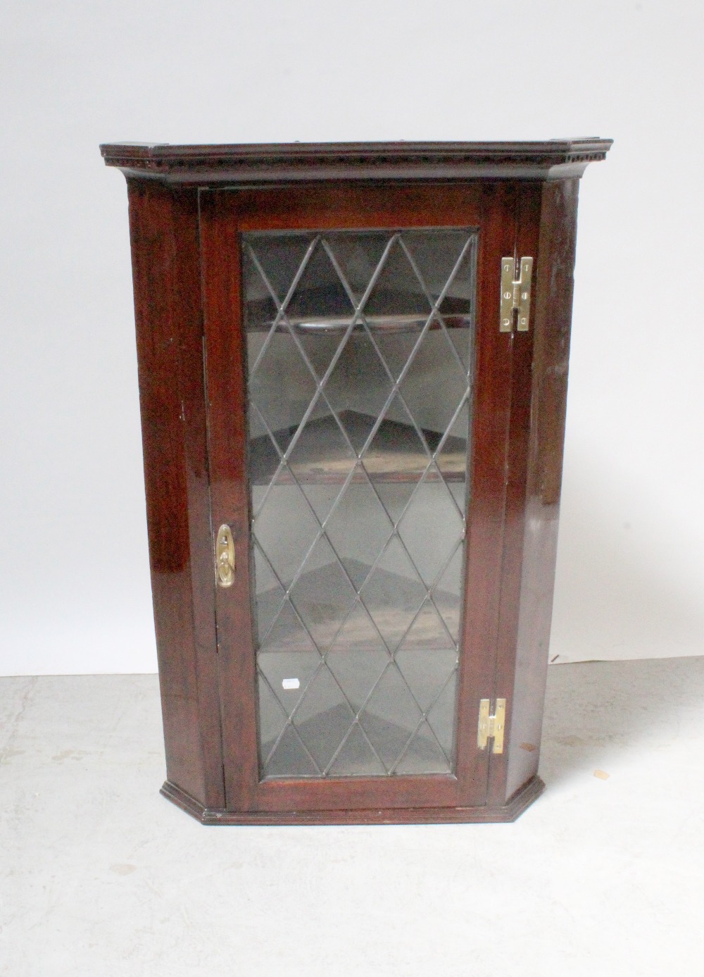 A Georgian mahogany wall-hanging corner cupboard with dentil moulded cornice above leaded glazed