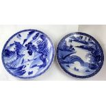 Two large Japanese blue and white pottery chargers, both decorated with pagoda, bridge,