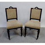 A pair of mahogany upholstered dining chairs with turned front supports to brass caps and castors