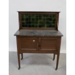 An Edwardian oak marble-topped wash stand with green tiled back and cupboard doors,