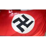 A large red ground, building drape style banner/flag bearing black swastika on white background,
