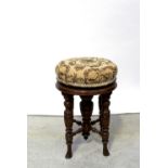 An Edwardian mahogany circular adjustable piano stool with upholstered woven seat on turned legs,