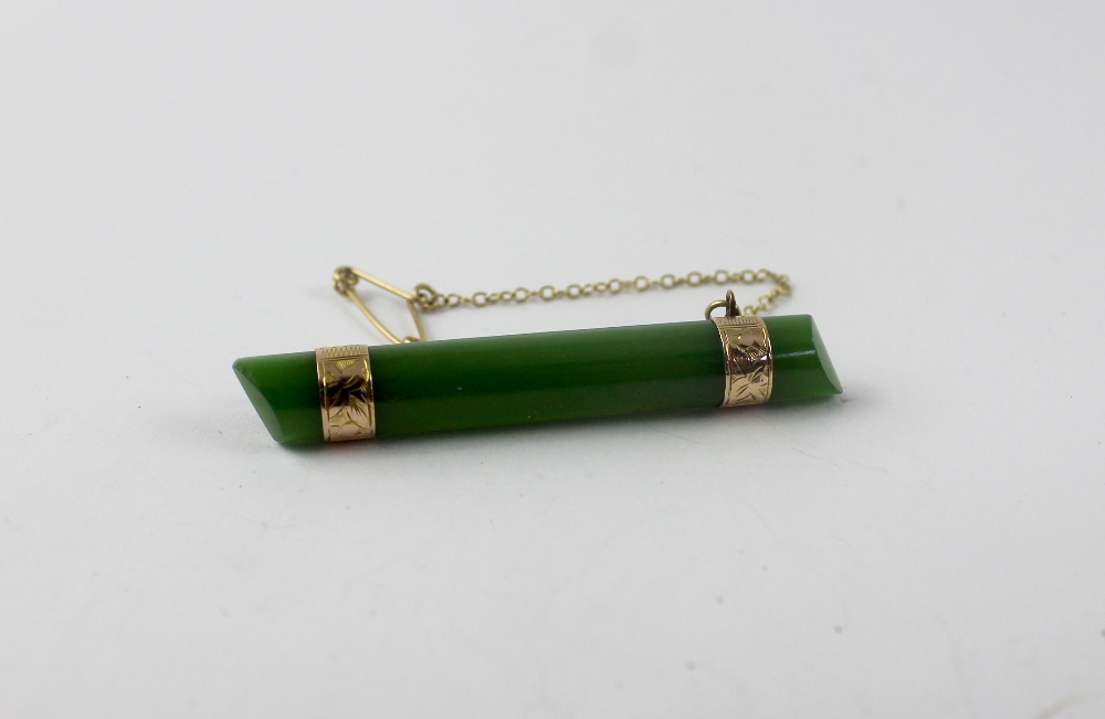A jade bar brooch with yellow metal fittings, length 5.5cm.