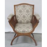 An Edwardian inlaid mahogany Savonarola chair with shield-shaped back upholstered in floral