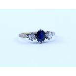 A 9ct gold three-stone ring set with central oval sapphire and two diamonds in platinum claw