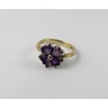 A 9ct gold dress ring set with four pale purple stones and diamond chip, size I, approx 2.5g.