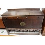 An early 20th century oak sideboard comprising two short drawers over a pair of cupboard doors with