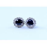 A pair of 14ct white gold earrings set with central oval sapphire,