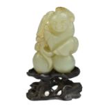 A Chinese jade carving depicting a boy holding two peaches, length 5.5cm, on carved hardwood stand.