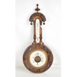 A circa 1900 carved walnut and beech wheel barometer with relief carved detail and upper