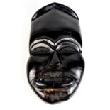 A large Japanese noh mask with animal hide detail and ebonised finish, length 67cm.