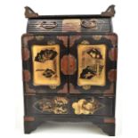 An early 20th century Japanese lacquered jewellery cabinet with central drawer above two panelled