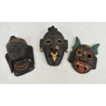 A Southeast Asian demon mask with painted and gilt detail, length approx 21cm, and two further