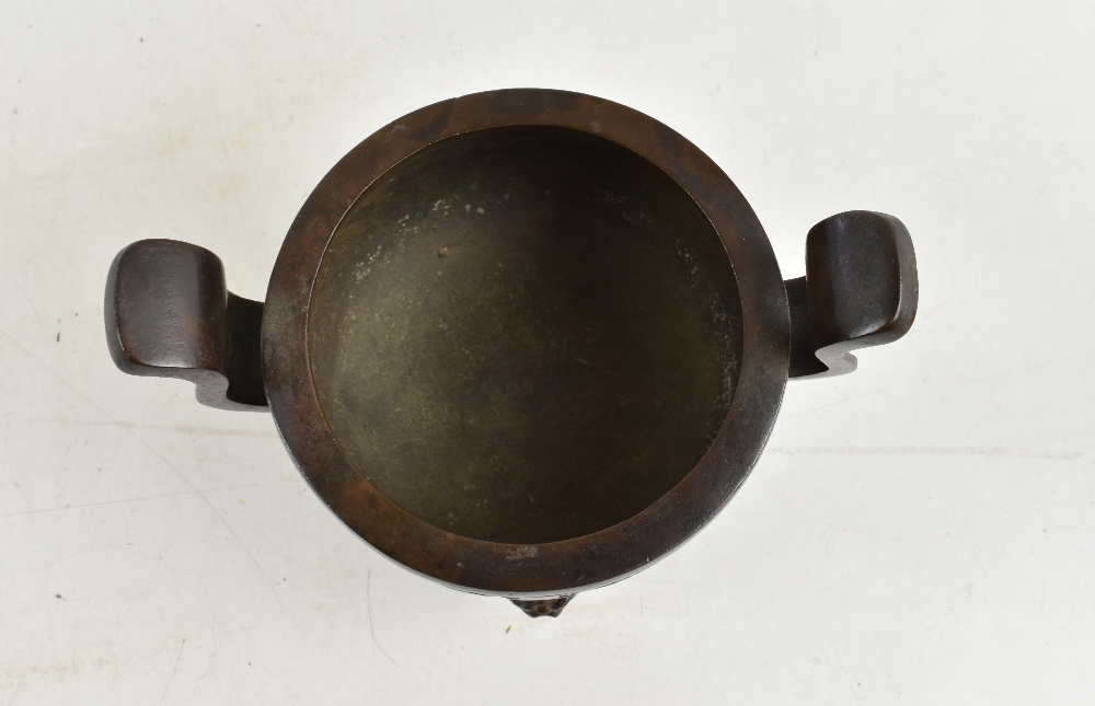 A 19th century Chinese bronze censer with twin raised handles and impressed decoration, on three - Image 2 of 9