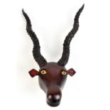 A late 19th/early 20th century naively carved wooden animal head, set with ibex horns, height 51cm.