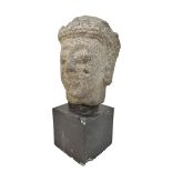 A large Javanese carved volcanic stone bust, height 28cm, now mounted on a wooden plinth.