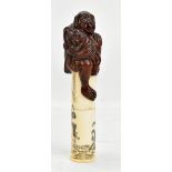 A Japanese bone scroll holder with applied mother and baby ape finial, the body decorated with