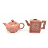 Two Chinese Yixing clay teapots including a rectangular example with embossed symbols, each with