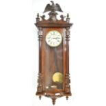 An early 20th century stained walnut cased Vienna style wall clock, with carved eagle surmount,