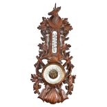 An early 20th century Black Forest barometer, with stag's head finial above carved oak leaves and