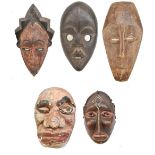 Four African carved wooden masks including a Dan example and one Javanese example (lower left as