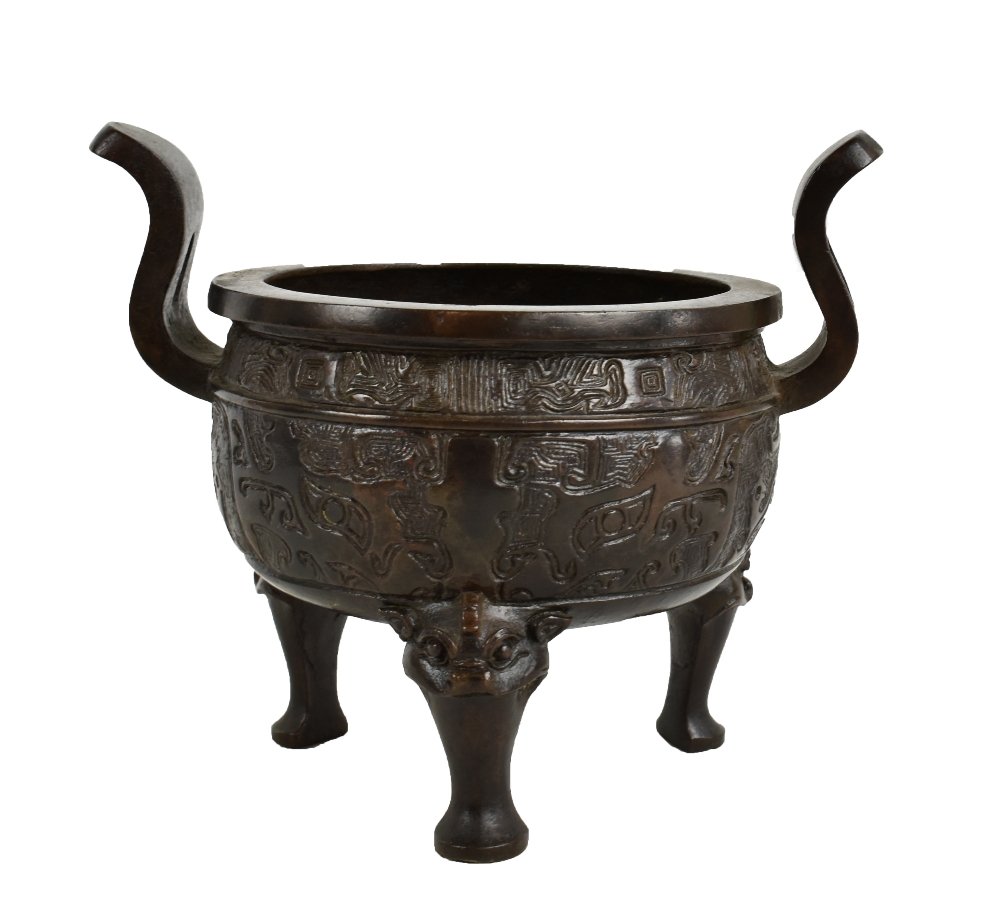 A 19th century Chinese bronze censer with twin raised handles and impressed decoration, on three