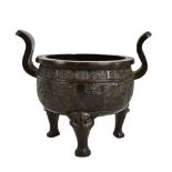 A 19th century Chinese bronze censer with twin raised handles and impressed decoration, on three