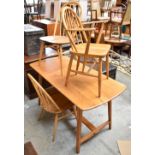 ERCOL; a mid century light elm refectory table raised on tapering block supports, height 73.5cm,