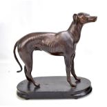 An early 20th century spelter figure of a greyhound or whippet mounted on an oval wooden plinth,