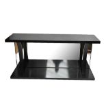A contemporary ebonised glass top console table, with mirror back flanked by waisted supports,