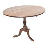 A George III oak tilt top table on ring turned column to three out swept legs, 69 x 92.5 x 83.5cm