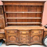 An early 19th century oak and inlaid break front dresser with plate rack back above an arrangement