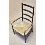 LIBERTY & CO; an early 20th century stained beech ladder back arm chair with rush seat on