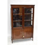 An Edwardian line inlaid mahogany twin door display cabinet, the twin astragal glazed doors