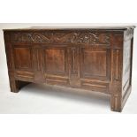 An 18th century carved oak coffer with carved and panelled decoration to the front and engraved