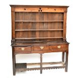 An 18th century oak dresser, the upper section with pierced frieze above three shelves, the base