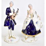 ROYAL DUX; a pair of 20th century figurines depicting a male musician and a lady holding a fan,