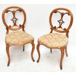 A set of four Victorian walnut balloon back dining chairs with elaborate carved splat, padded