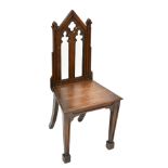 A Victorian Gothic Revival oak hall chair with pierced detail to the back, raised on block supports,