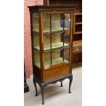 An Edwardian mahogany display cabinet, the glazed door enclosing three shelves above carved frieze