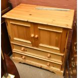 A modern pine cabinet with two panelled doors above two base draws raised on bracket feet, height