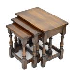 A nest of three reproduction oak coffee tables, raised on block supports, height of largest 48cm,