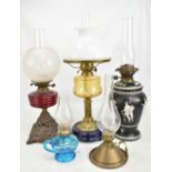 Five late 19th/early 20th century oil lamps of varied size and form, the largest with opaque white