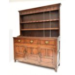 An 18th century oak dresser, the plate rack back with two fixed shelves and iron hooks above three