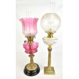 Two late 19th century oil lamps, the first with cranberry shade and reservoir, height excluding